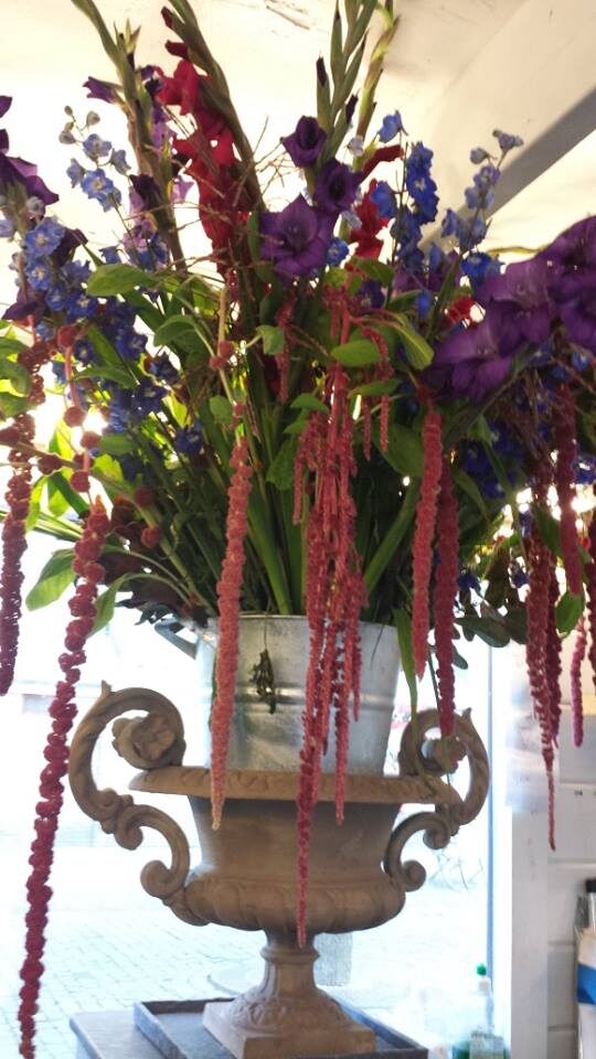 Hoog bloemstuk met amaranthus in een antieke tuinvaas